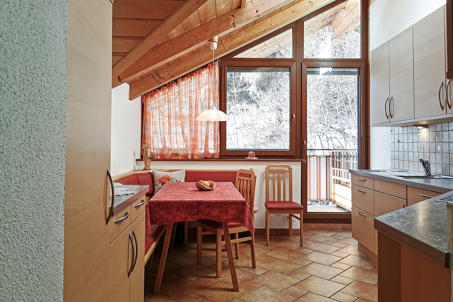 Cucina luminosa e accogliente con ampia vetrata, angolo pranzo confortevole e tutto il necessario per cucinare.